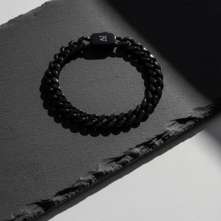 Bracelet chaîne noir posé sur surface sombre