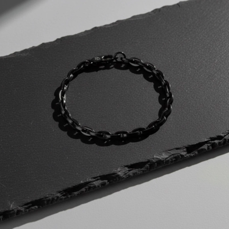 Bracelet chaîne noir posé sur surface sombre