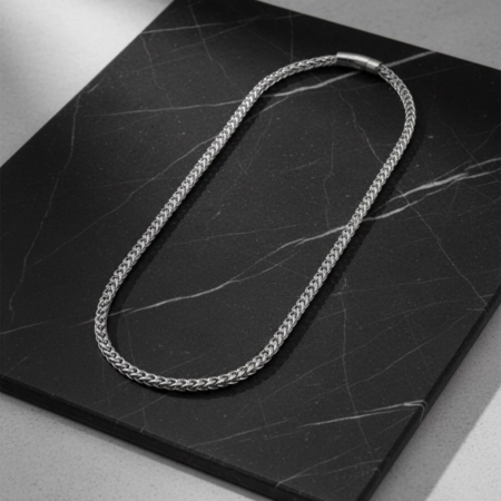 Silver chain necklace on black marble